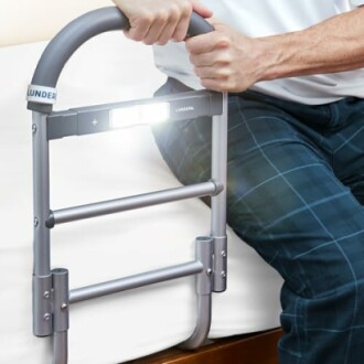 Person using a bed assist rail with built-in light.