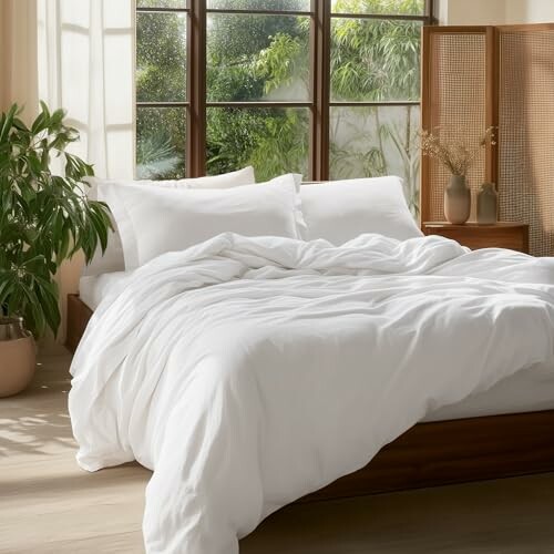 Cozy bedroom with white bedding and plants.