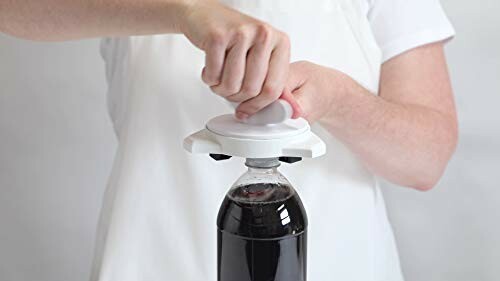 Person using a white bottle opener on a soda bottle.